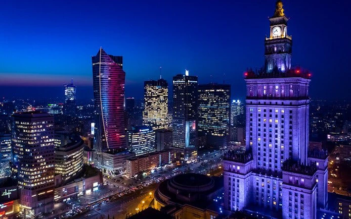 Warsaw skyline at night with illuminated Palace of Culture and Science.