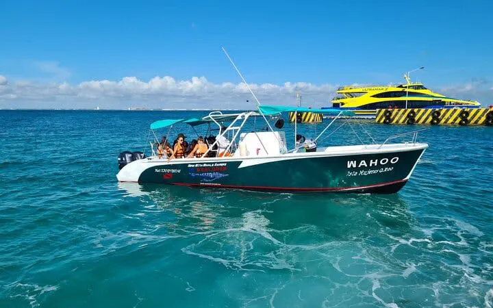 Boat with tourists on Whale Shark Snorkel Tour near reef, clear blue water, and docked ferry.