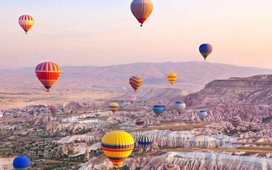 Hot air balloons floating over Cappadocia's unique rock formations at sunrise.