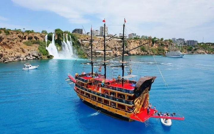 Pirate-themed boat near Lower Duden Waterfall in Antalya, with other boats and coastal view.
