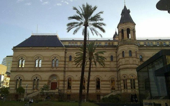 University of Adelaide historic building with palm trees, part of self-guided audio tour.