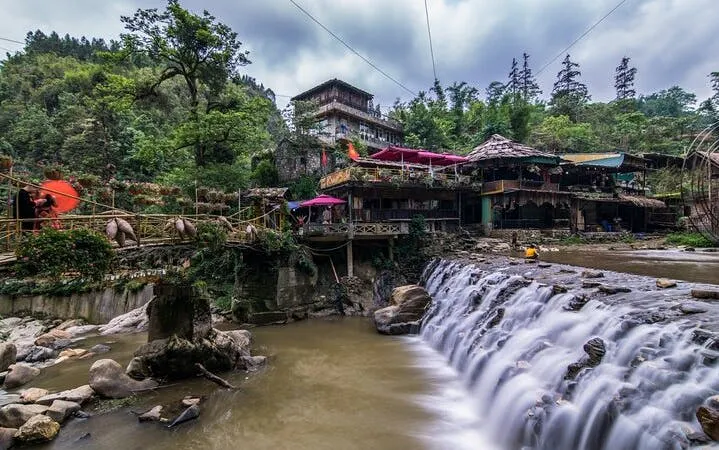 Sapa village with waterfall, traditional buildings, and lush greenery on motorbike sightseeing tour.
