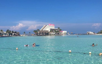 Catamaran tour guests snorkeling in clear waters near Isla Mujeres beach club.
