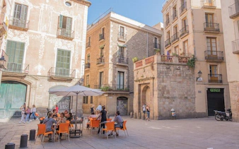 Outdoor café in a historic square in Gothic Barcelona, part of a self-guided city exploration game.
