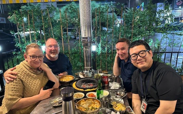 Small group enjoying Korean BBQ dinner in Gangnam, Seoul, with modern city backdrop.