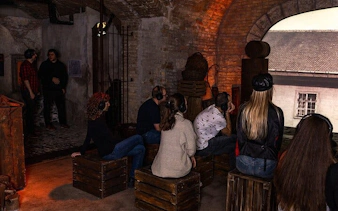 Visitors seated with headphones in a dimly lit room at Time Machine Budapest exhibition.