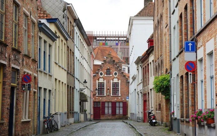 Narrow cobblestone street in Bruges lined with historic brick buildings.
