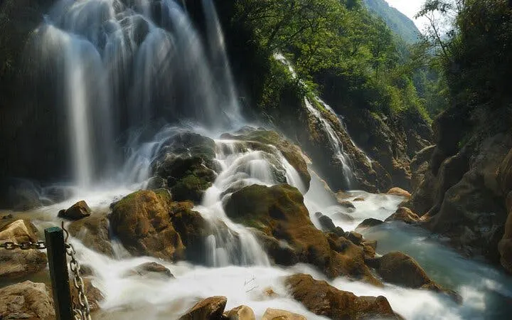 Silver Waterfall cascading over rocks surrounded by lush greenery in Sapa, Vietnam.