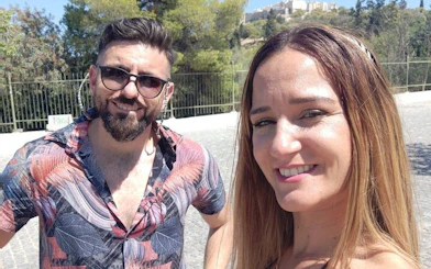 Couple enjoying Athens city exploration with Acropolis in the background.