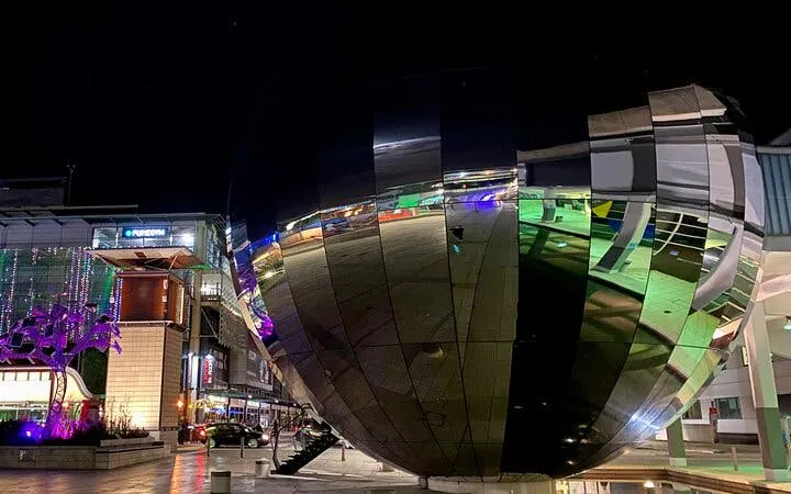 Bristol city center at night with illuminated modern architecture reflecting lights.