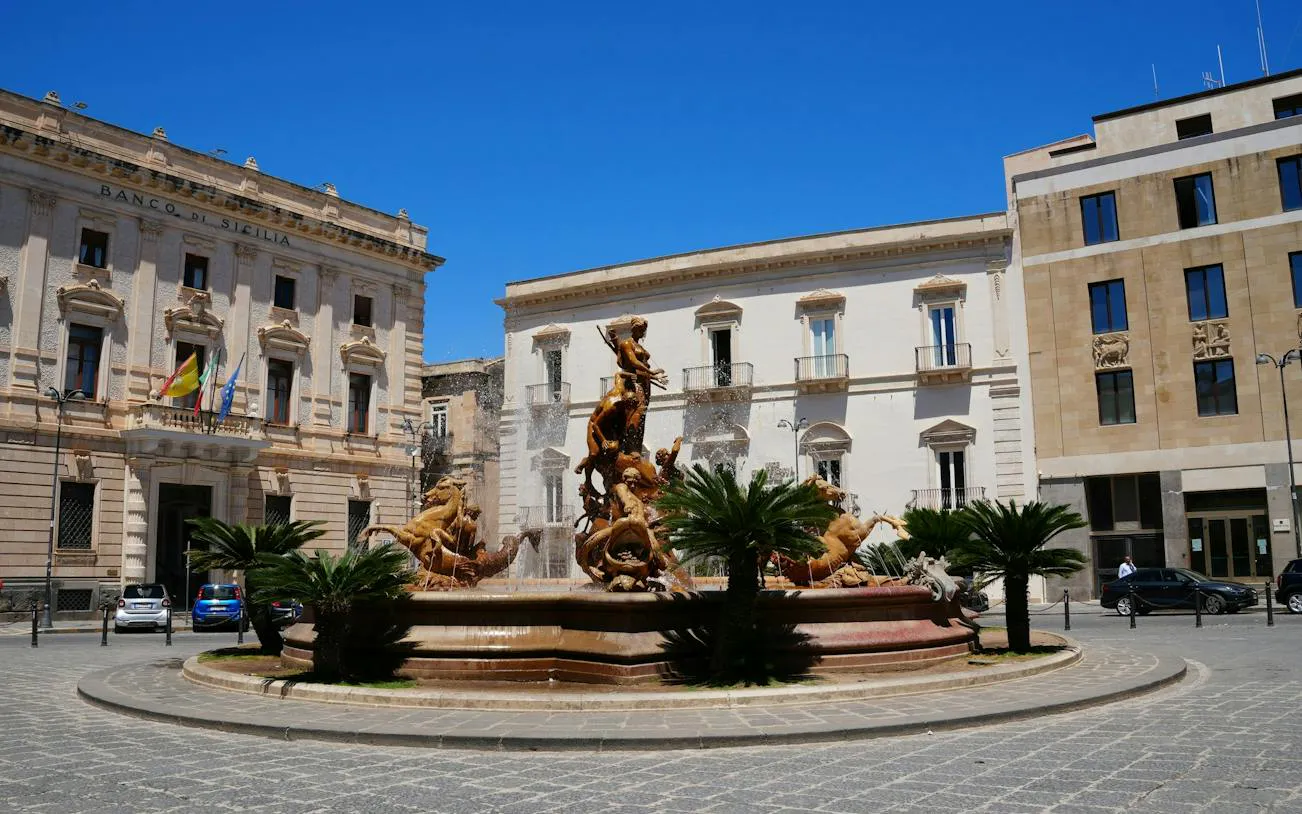 Fountain of Diana in Ortigia, Siracusa, with historic buildings in the background.