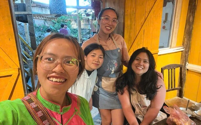 Bun Cha cooking class participants in a cozy Vietnamese kitchen setting.