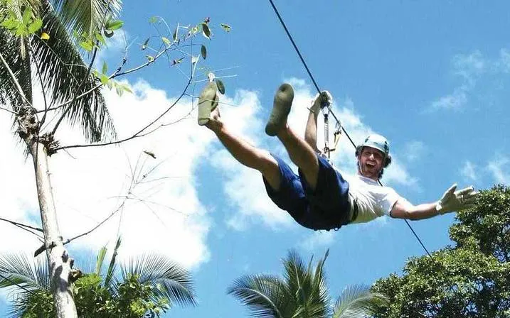Person ziplining through tropical trees on Koh Samui 4WD Jeep Safari Tour.