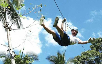 Person ziplining through tropical trees on Koh Samui 4WD Jeep Safari Tour.