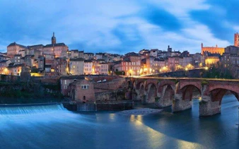 Albi's Pont Vieux bridge over Tarn River at dusk, part of self-guided audio tour in Toulouse.