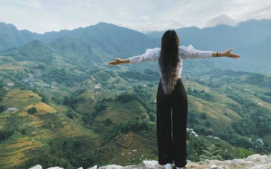 Person overlooking Sapa rice terraces and mountains during trekking tour in Vietnam.