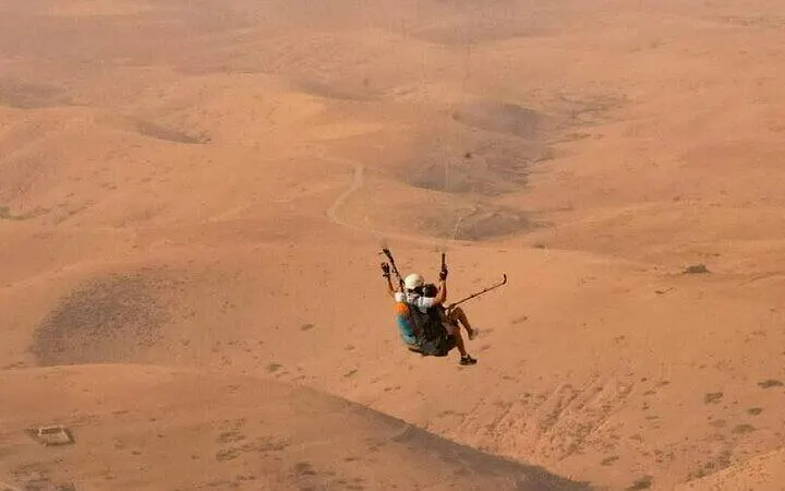 Paragliding over Atlas Mountains desert landscape near Marrakech.