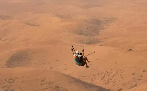 Paragliding over Atlas Mountains desert landscape near Marrakech.