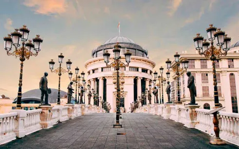 Skopje bridge with statues leading to the Archaeological Museum, featured in self-guided walking tour.