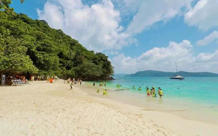 Visitors enjoying Banana Beach on Koh Hey with clear waters and lush greenery, Phuket.