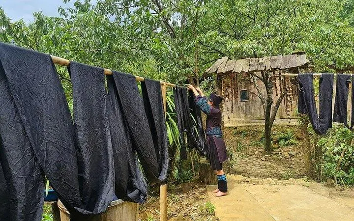 Indigo-dyed fabric drying in Ta Van Village, Sa Pa, with H’Mong artisan adjusting cloth.
