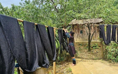 Indigo-dyed fabric drying in Ta Van Village, Sa Pa, with H’Mong artisan adjusting cloth.
