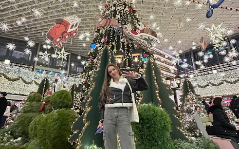 Visitor posing in front of a decorated Christmas tree at Starfield Library, Seoul during Gangnam Walking Tour.