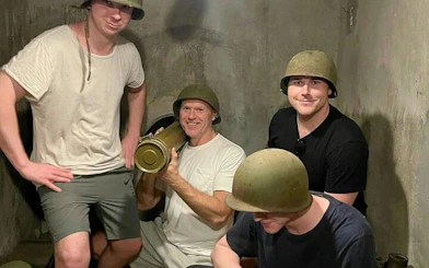 Tourists wearing helmets explore a historical site in Ho Chi Minh City during a motorbike street food tour.