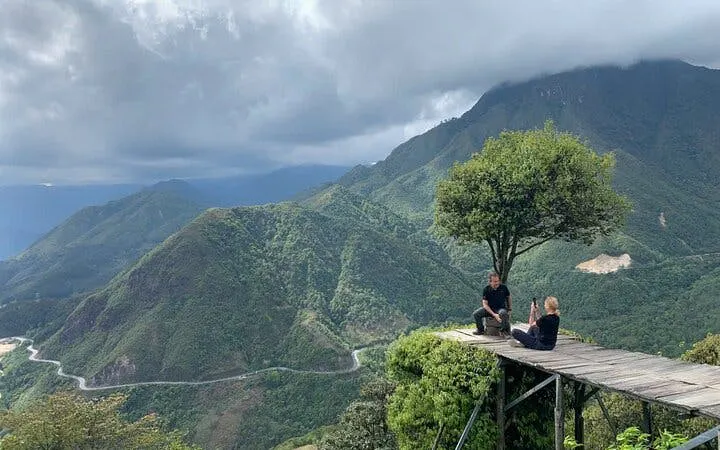 Sapa motorbike tour with travelers on a wooden platform overlooking lush valleys and mountains.