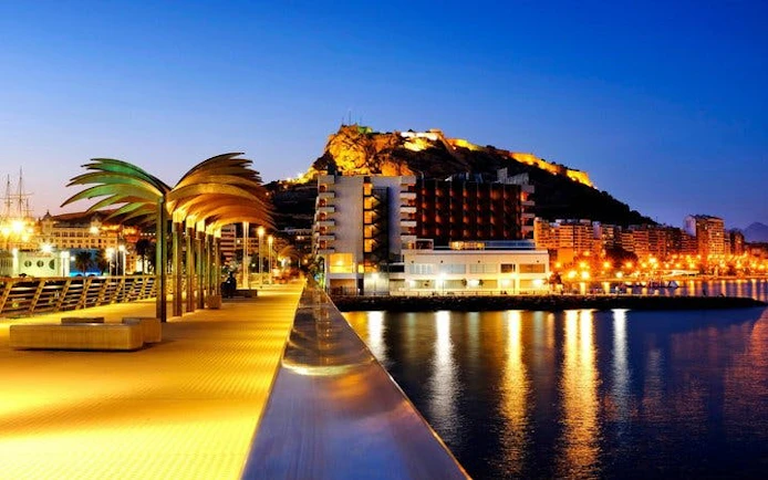 Alicante waterfront view with Santa Bárbara Castle illuminated at night.
