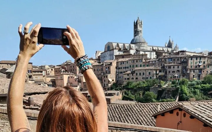 Person photographing Siena's skyline with cathedral, Tuscany day trip.