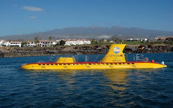 Yellow submarine on Tenerife waters with coastal view and mountain backdrop.