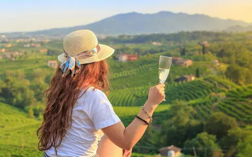 Person enjoying wine overlooking Prosecco Hills vineyard near Venice.