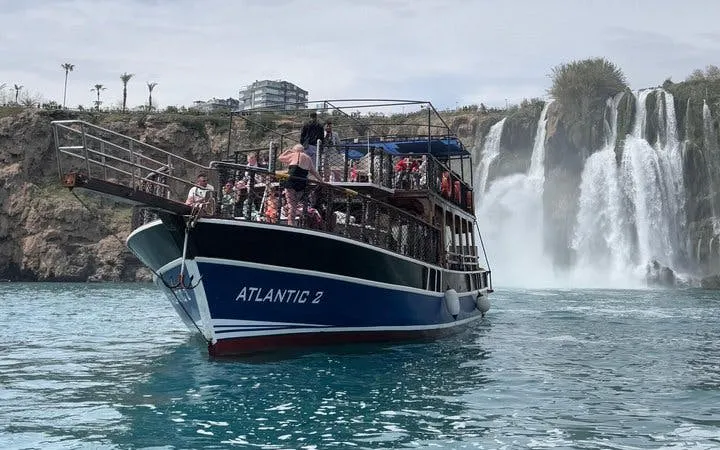 Boat approaching Antalya's Lower Duden Waterfall during a tour with lunch and drinks included.