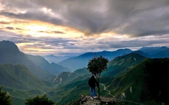 Mountain view in Sapa at sunset with a person standing on a ledge, Vietnam.