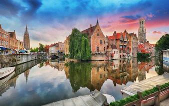 Bruges canal view with historic buildings and Belfry tower at sunset, part of Bruges and Ghent day trip.