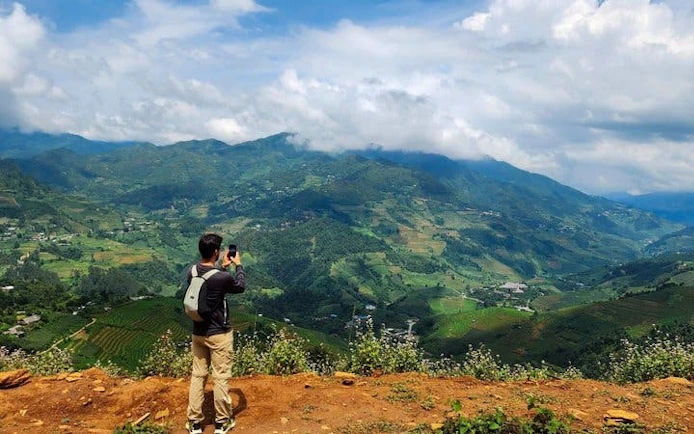 Trekker photographing terraced rice fields in Mu Cang Chai, Vietnam.