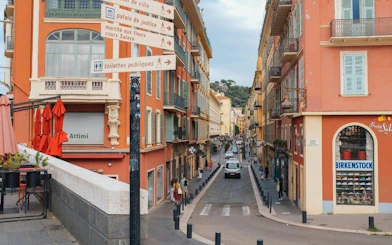 Street view in Nice with colorful buildings and directional signs for a self-guided walking tour.