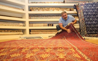 Local vendor displaying traditional Turkish carpets in Cappadocia shop.