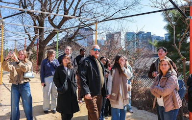 Group of tourists exploring Gangnam, Seoul, with city skyline in the background.