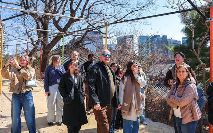 Group of tourists exploring Gangnam, Seoul, with city skyline in the background.