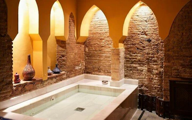 Authentic Moroccan hammam interior with arched niches and decorative vases in Marrakesh.