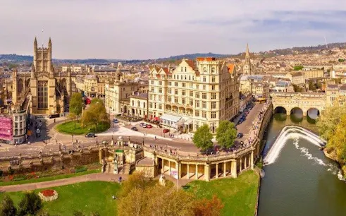 Bath cityscape with historic buildings, river, and Pulteney Bridge, view from self-guided walking tour.