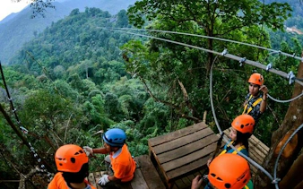 Zipline platform in Chiang Mai jungle with participants in helmets preparing for descent.