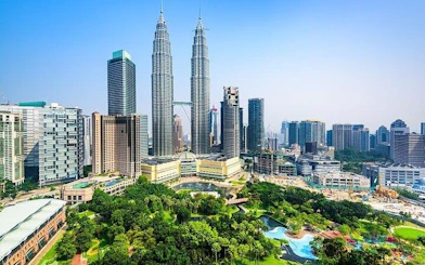 Petronas Towers and Kuala Lumpur skyline with lush park in foreground.