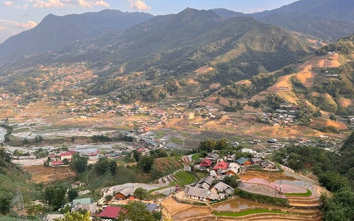Terraced rice fields and village houses in Cat Cat Village, Sa Pa, with mountain backdrop.