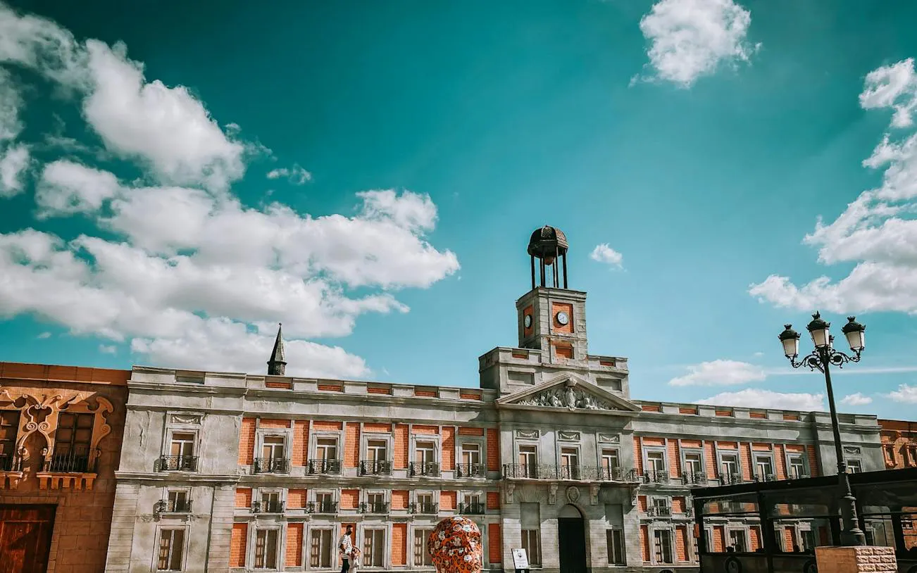 Puerta del Sol clock tower in Madrid's historic center under a blue sky.