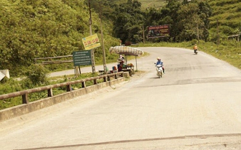 Motorbike on rural road near Bac Ha Market, Sapa, with roadside vendor stand.