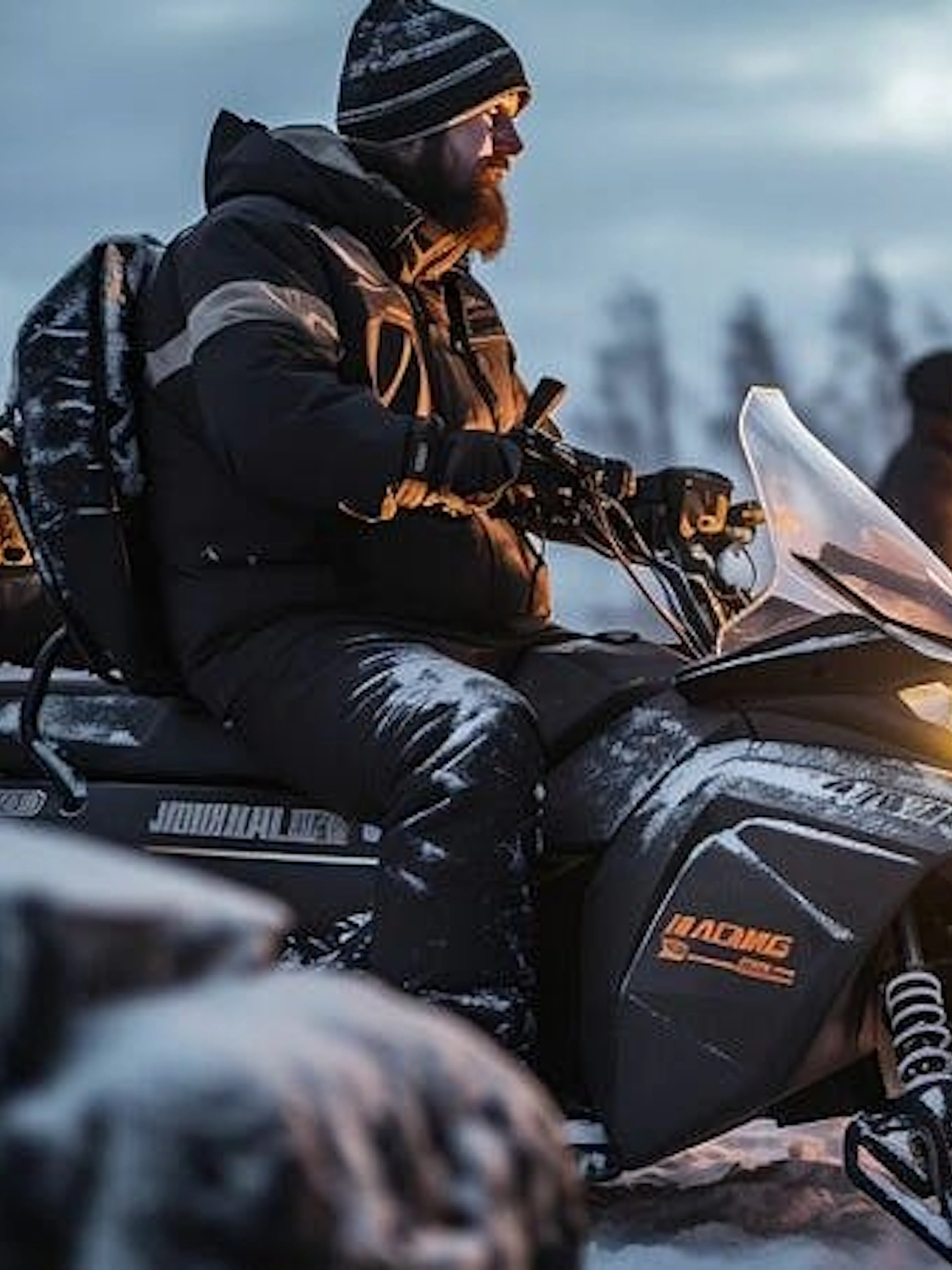 Snowmobile riders in Zakopane with a bonfire in the background during a guided adventure.