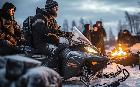 Snowmobile riders in Zakopane with a bonfire in the background during a guided adventure.